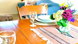 Une table à manger avec un vase en verre rempli de fleurs, des assiettes et un verre à vin.