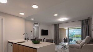 A modern kitchen with a sink, a green bowl, and a dining area with a glass table and chairs.