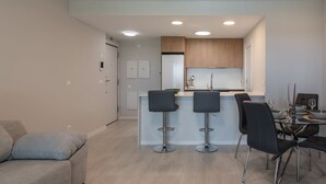 A modern kitchen with a central island, bar stools, and a dining table set for four.