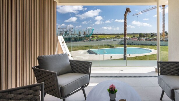 A modern balcony with a view of a swimming pool and industrial structures.