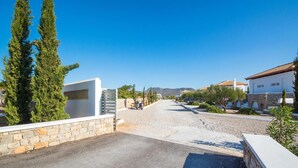 A residential street with houses, a stone wall, and a clear blue sky.
