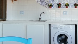 Une cuisine équipée d’un lave-linge, avec une chaise bleue et un plafond en bois.