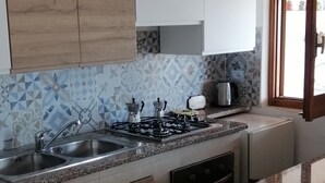 Une cuisine équipée d’une cuisinière à gaz, d’un évier et de meubles de rangement en bois.