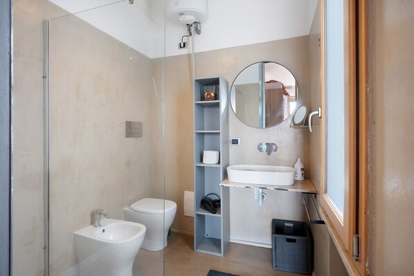 Un baño moderno con cabina de ducha de vidrio, inodoro, bidé, lavabo y espejo.