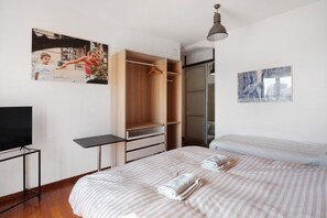 Une chambre à coucher avec un lit, une armoire en bois, un téléviseur et un tableau accroché au mur.
