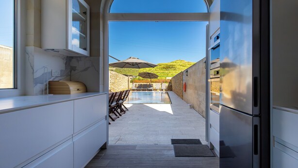 Une cuisine moderne avec vue sur une piscine et un espace salon extérieur.