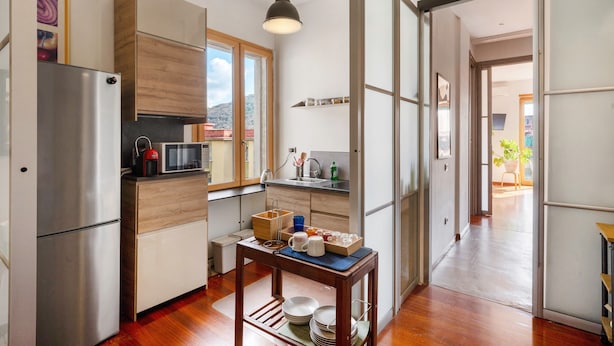 Una cocina moderna con refrigerador, microondas, gabinetes de madera y una mesa de comedor con vajilla.