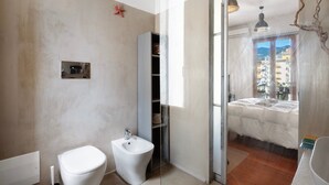 Un baño con inodoro, bidé y cabina de ducha de vidrio.