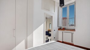 Un dormitorio con cama, armario, ventana con vistas y radiador.