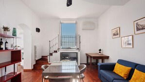 Un espacio habitable moderno con comedor, un sofá azul y una escalera que sube a un nivel superior.