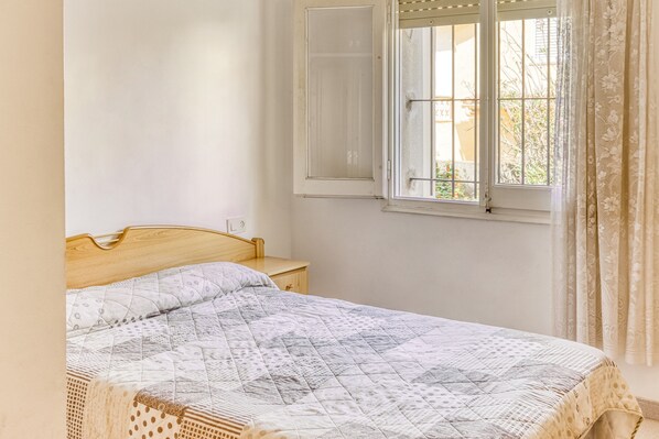 Une chambre à coucher avec un lit en bois, une fenêtre donnant sur un beau paysage et un rideau.