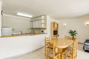A compact kitchen with a microwave, sink, and wooden dining table with chairs.