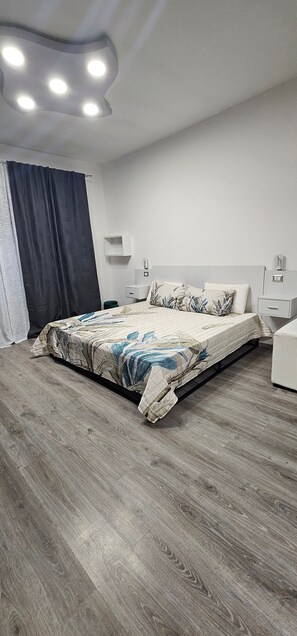 A bedroom with a bed, bedside tables, a nightstand, a wardrobe, and a ceiling light fixture. - Room 'Quadrupla' with Shared Terrace, Wi-Fi and Air Conditioning (Roma)