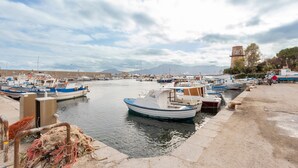 Un port de plaisance avec des bateaux amarrés, un ciel dégagé et une montagne lointaine.