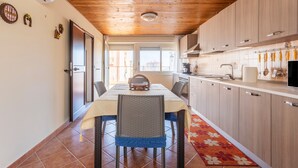 Un espace repas comprenant une table, des chaises et une cuisine équipée de meubles et d’appareils électroménagers.