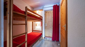 A bunk bed room with a wooden door and red curtains. - Nice and bright apt for 4 pers (Morillon)