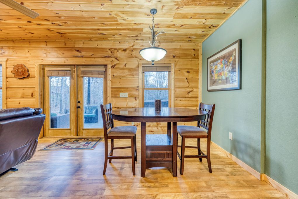 L’intérieur d’un chalet en bois comprend une table à manger, des chaises, un canapé et un tableau encadré accroché au mur.