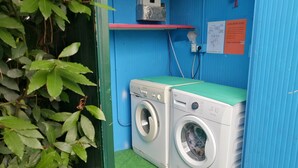 A compact laundry area with two washing machines, a small shelf with a heater, and a wall-mounted instruction sign. - Euroholiday Village 4R Apartment with Shared Terrace, Garden and Wi-Fi (Jesolo)