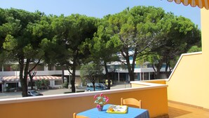 A balcony with a table set for two, a chair, and a potted plant. - Apartment 'Simma' with Balcony and Air Conditioning (SAN MICHELE AL TAGLIAMENTO)