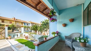 A balcony with wicker furniture, potted plants, and a view of the street. - Casa Vacanze 'EliFra' with Private Terrace, Garden, and Balcony (San Giovanni Suergiu)