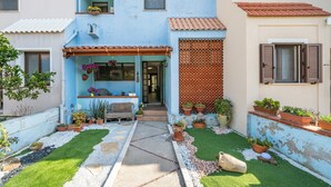 A courtyard with a pathway, potted plants, a bench, and a small table. - Casa Vacanze 'EliFra' with Private Terrace, Garden, and Balcony (San Giovanni Suergiu)