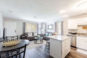 A modern kitchen with white cabinets, a marble countertop, and a built-in dishwasher.