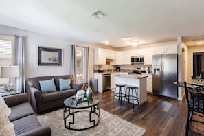 A modern kitchen with white cabinets, stainless steel appliances, and a central island with stools. - Sports Village | All Amenities Included | Q9 (Saint George)