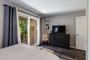 A bedroom with a bed, a TV, a dresser, and a chair.