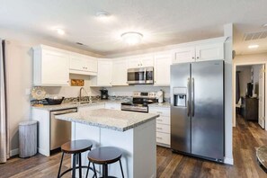A modern kitchen with white cabinets, stainless steel appliances, and a granite countertop.