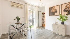 Ein moderner Essbereich mit einem Glastisch und Stühlen, einem Holzschrank und Bildern an der Wand.