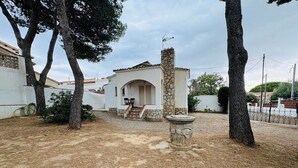 A white building with a stone chimney, a small porch, and a stone fountain in the yard. - Holiday Home 'El Pozo - 400m from Riells Beach' with Terrace, Garden and Balcony (L'Escala)