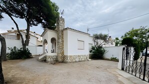A residential property with a stone chimney, a gated entrance, and a paved driveway. - Holiday Home 'El Pozo - 400m from Riells Beach' with Terrace, Garden and Balcony (L'Escala)