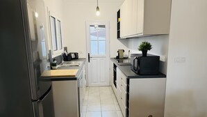 A compact kitchen with a refrigerator, sink, and microwave. - Holiday Home 'El Pozo - 400m from Riells Beach' with Terrace, Garden and Balcony (L'Escala)