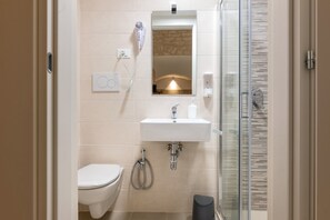 Ein modernes Badezimmer mit Toilette, Waschbecken, Spiegel und einer Duschkabine aus Glas.