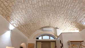 A room with a stone ceiling, an arched doorway, and a white wall with a door.