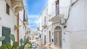 A narrow street with buildings on either side, a cactus in the foreground, and a clear sky.