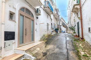 A narrow street with buildings on both sides, a visible door, and a small step leading to the entrance. - Studio 'La Pizzicata' with Wi-Fi and Air Conditioning (Ostuni)