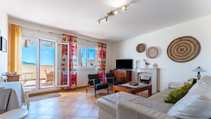 Ein geräumiges Wohnzimmer mit Sofa, Sesseln, Couchtisch, Fernseher und Kamin.