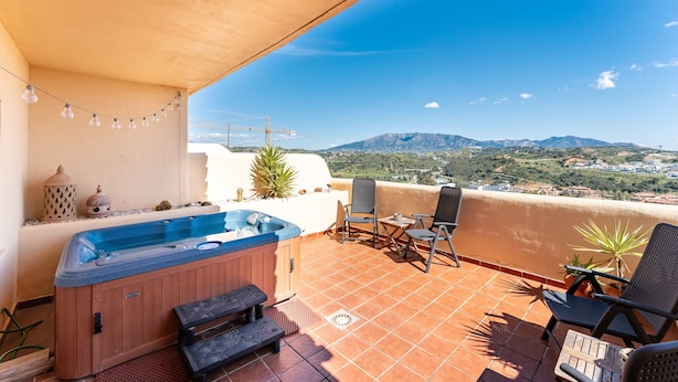 Ein Whirlpool, Terrassenstühle und Blick auf Berge.
