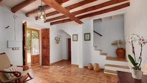 A rustic interior with a wooden rocking chair, a staircase, and a potted orchid.