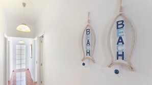 A hallway with a polished wooden floor, a white door, and two wall-mounted decorations spelling 'BEACH.'