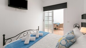 A bedroom with a bed, a flat-screen TV, a window, and a view of an outdoor area.
