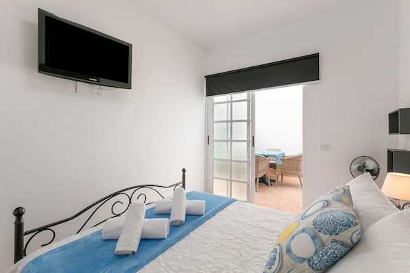 Une chambre avec un lit, un téléviseur à écran plat, une fenêtre et une vue sur un espace extérieur.