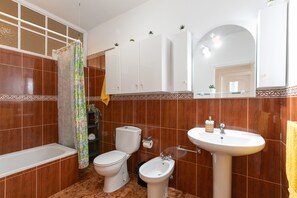 Une salle de bain équipée d’une baignoire, de toilettes, d’un bidet et d’un lavabo.