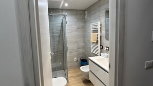 Et moderne badeværelse med bruser, toilet og vaskebord.