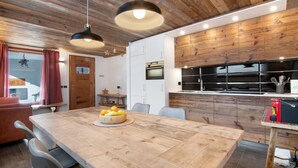 A modern kitchen with wooden cabinets, a central island, and a dining area with a wooden table and chairs.