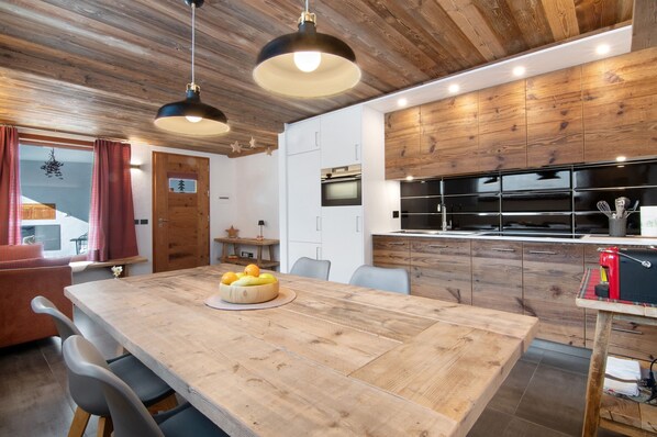 A modern kitchen with wooden cabinets, a central island, and a dining area with a wooden table and chairs.