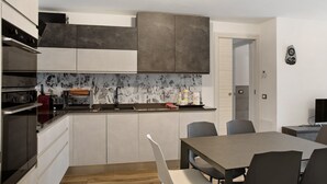 A modern kitchen with built-in appliances, a dining area with a table and chairs, and a small seating area. - Apartment 'Giorgia - Caspoggio' with Mountain View, Shared Garden and Balcony (Caspoggio)