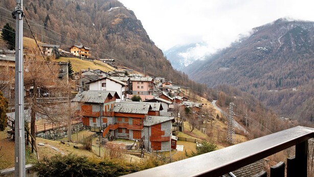 A mountainous village with traditional houses, a winding road, and a power line tower. - Apartment 'Giorgia - Caspoggio' with Mountain View, Shared Garden and Balcony (Caspoggio)