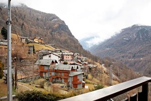 Un village de montagne aux maisons traditionnelles, avec une route sinueuse et un pylône de ligne électrique.